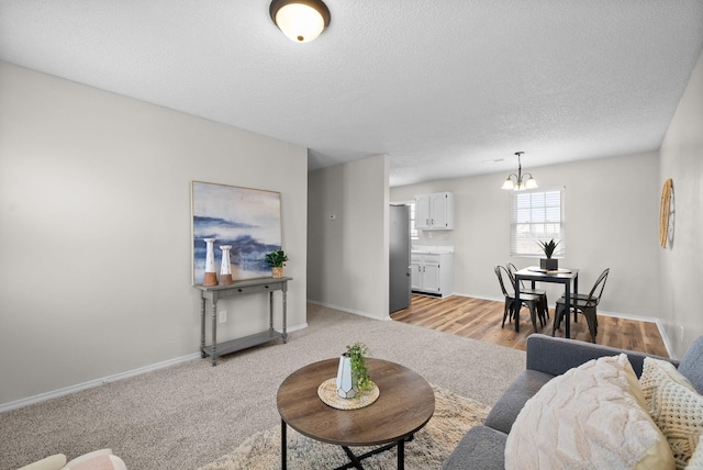 living room featuring a textured ceiling, light carpet, and an inviting chandelier