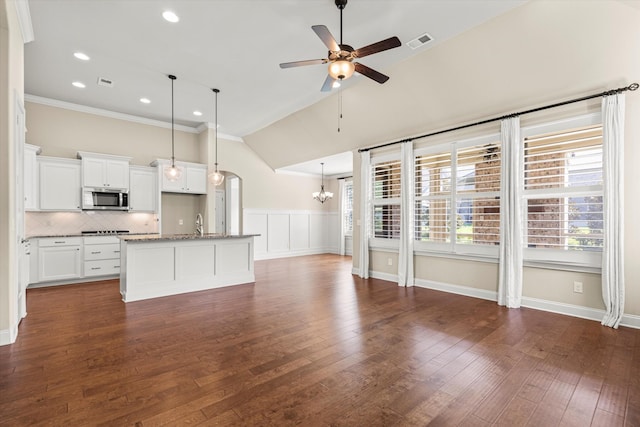 interior space featuring white cabinetry, an island with sink, hanging light fixtures, a wealth of natural light, and ceiling fan with notable chandelier