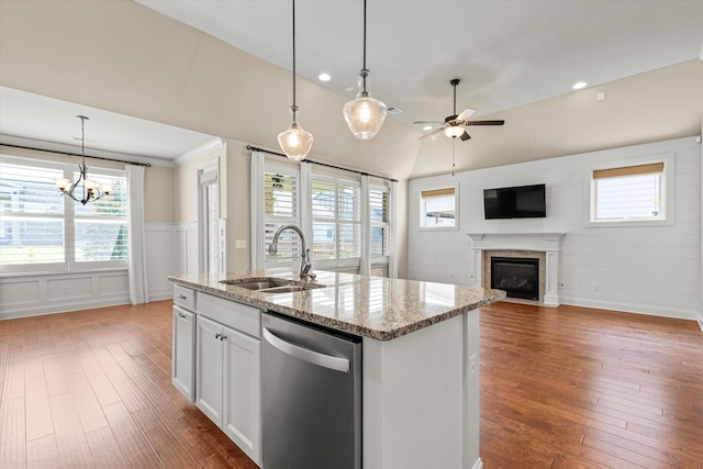 kitchen with a center island with sink, sink, light stone counters, dishwasher, and white cabinets