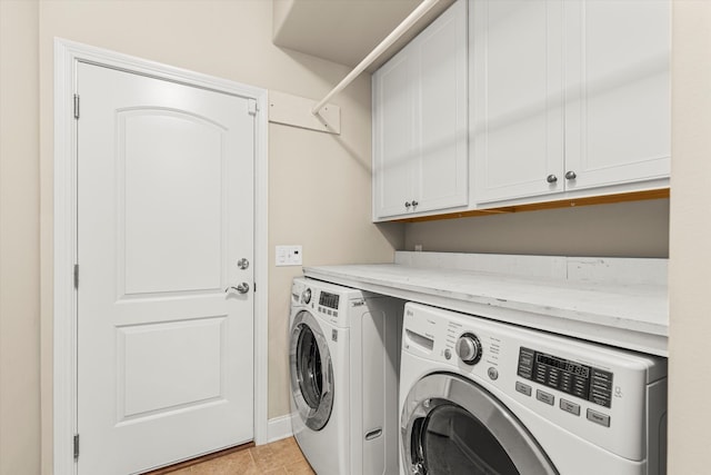 laundry room with light tile patterned floors, washer and dryer, and cabinets