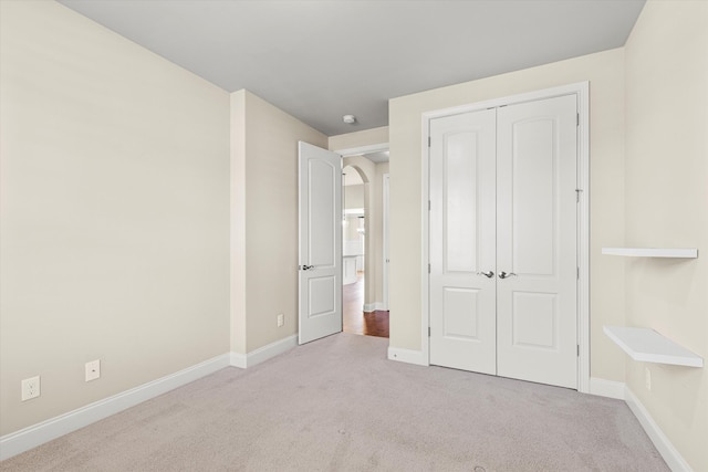 unfurnished bedroom with a closet and light colored carpet