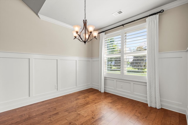 unfurnished dining area featuring a chandelier, wood-type flooring, and ornamental molding