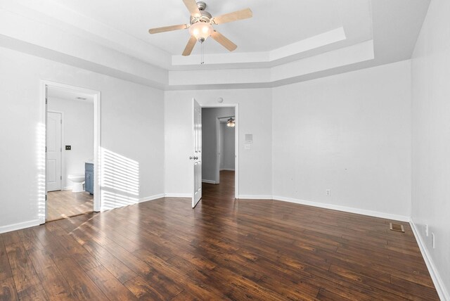 unfurnished room with a raised ceiling, ceiling fan, and dark hardwood / wood-style floors