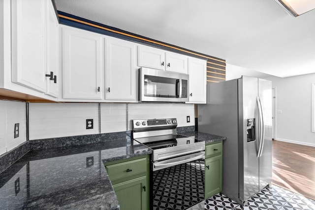 kitchen with appliances with stainless steel finishes, white cabinets, backsplash, dark stone countertops, and green cabinetry