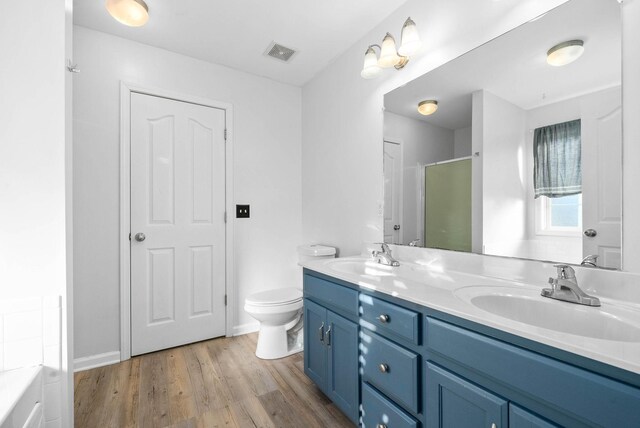 bathroom featuring toilet, a shower with door, vanity, and wood-type flooring