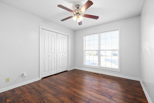 unfurnished bedroom featuring ceiling fan, a closet, and dark hardwood / wood-style flooring