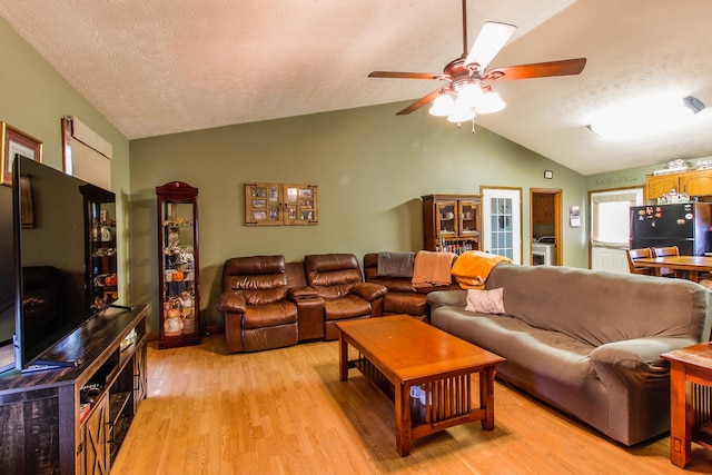 living room with light wood-type flooring, vaulted ceiling, a textured ceiling, and ceiling fan