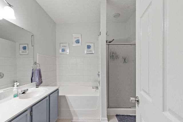 bathroom featuring a textured ceiling, separate shower and tub, and vanity