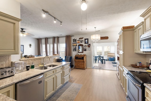 kitchen with sink, cream cabinets, stainless steel appliances, and pendant lighting