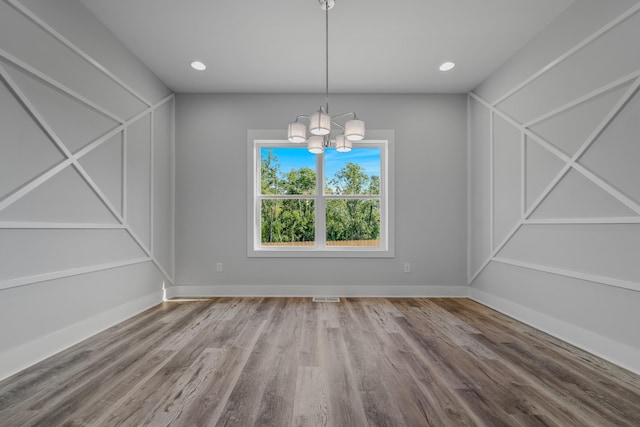 unfurnished dining area with a notable chandelier and wood-type flooring