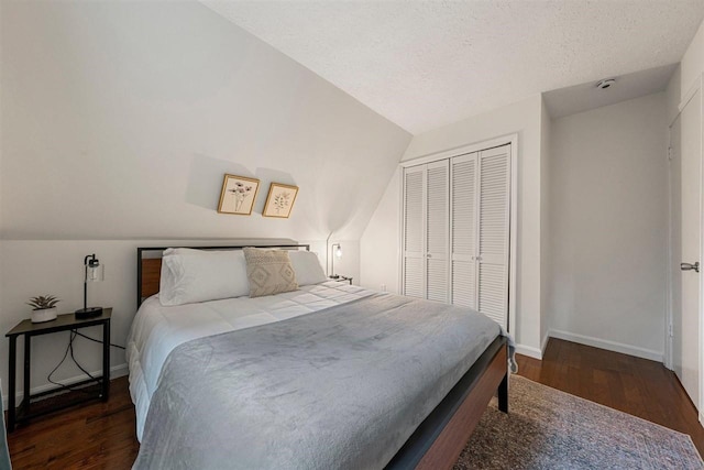 bedroom with dark hardwood / wood-style flooring, a textured ceiling, a closet, and lofted ceiling