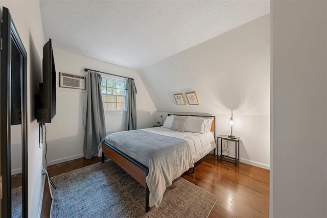 bedroom featuring hardwood / wood-style floors, lofted ceiling, a wall mounted AC, and a textured ceiling