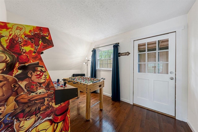 playroom with dark wood-type flooring, vaulted ceiling, and a textured ceiling