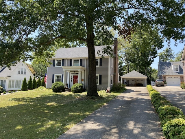 colonial house with a front yard, an outdoor structure, and a garage