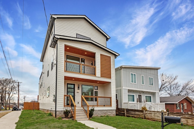 contemporary home featuring covered porch, a front yard, and a balcony