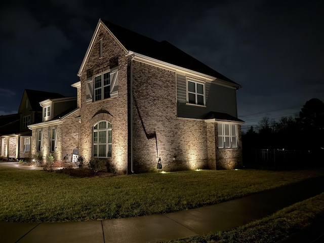 property exterior at night featuring a lawn