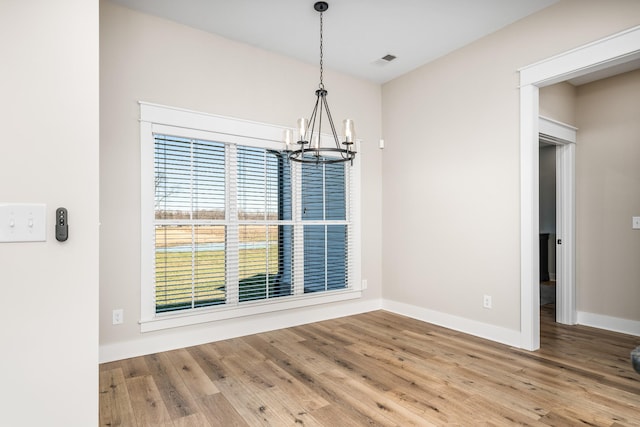 unfurnished dining area featuring a chandelier and wood-type flooring