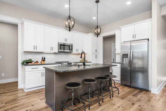 kitchen featuring appliances with stainless steel finishes, decorative backsplash, white cabinets, and a center island with sink