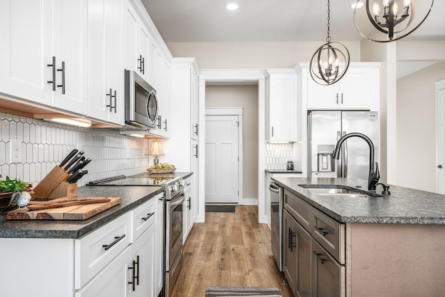 kitchen featuring sink, white cabinets, stainless steel appliances, and decorative light fixtures