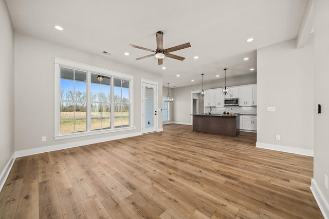 unfurnished living room featuring light hardwood / wood-style flooring and ceiling fan