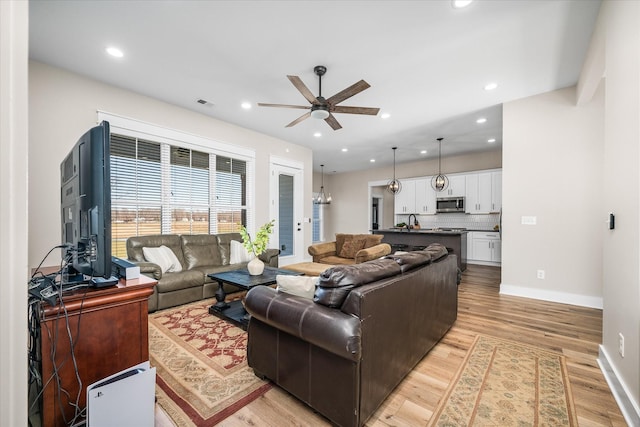 living room with light hardwood / wood-style flooring, ceiling fan, and sink