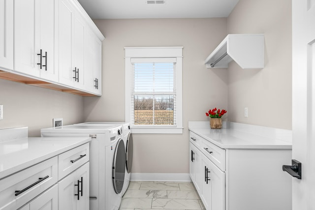 laundry room featuring washing machine and clothes dryer and cabinets