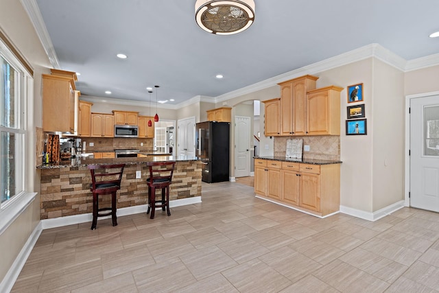 kitchen featuring kitchen peninsula, stainless steel appliances, decorative light fixtures, dark stone countertops, and a breakfast bar area