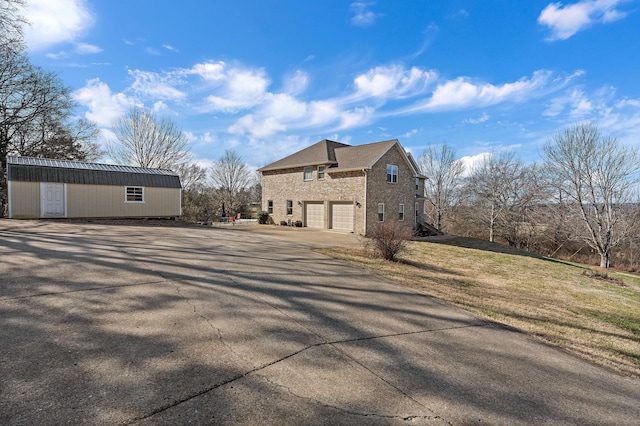 view of property exterior with a garage, a lawn, and an outdoor structure