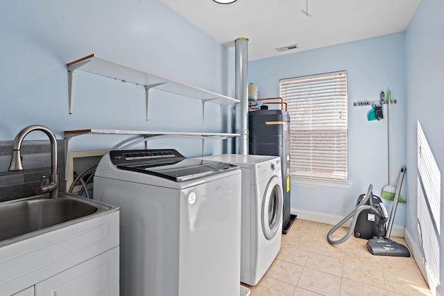 laundry area featuring washer and dryer, sink, water heater, and light tile patterned floors