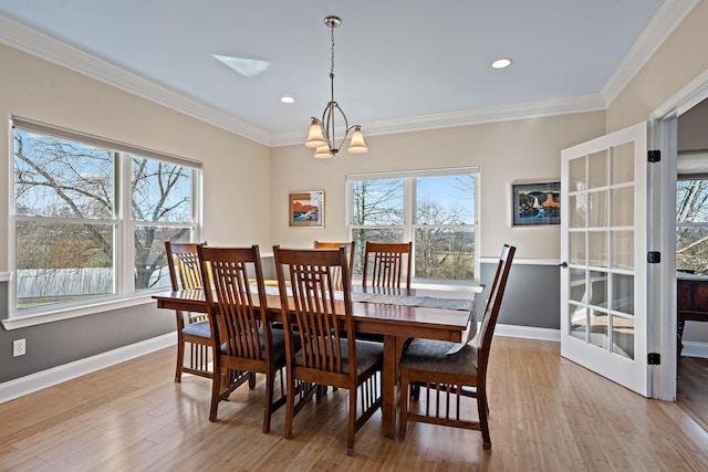 dining area with light hardwood / wood-style floors, plenty of natural light, crown molding, and a notable chandelier