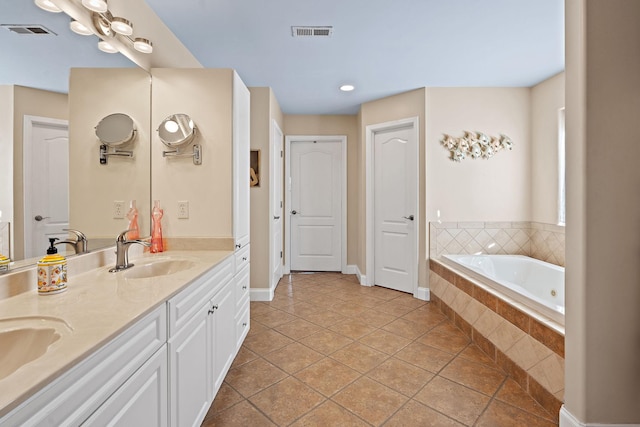 bathroom featuring vanity, tile patterned flooring, and tiled tub