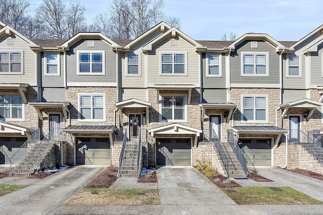 multi unit property featuring concrete driveway, a standing seam roof, an attached garage, and stairs