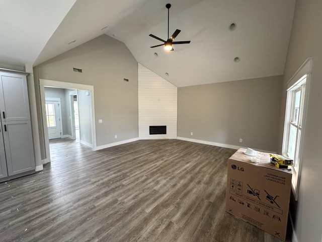 unfurnished living room featuring a large fireplace, high vaulted ceiling, dark hardwood / wood-style floors, and ceiling fan