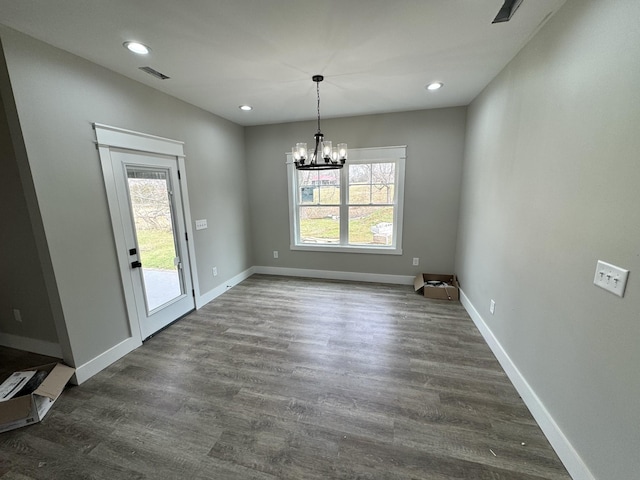 unfurnished dining area featuring a notable chandelier, dark hardwood / wood-style floors, and a wealth of natural light