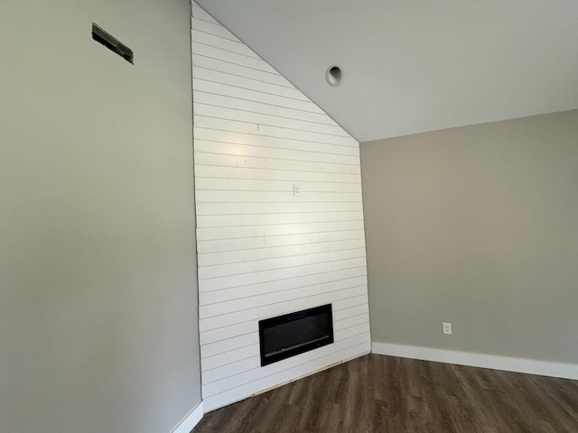 unfurnished living room featuring a large fireplace, dark wood-type flooring, and vaulted ceiling