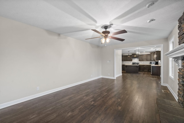 unfurnished living room with a textured ceiling, dark wood-type flooring, and ceiling fan with notable chandelier