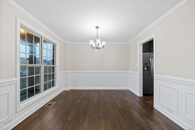 unfurnished dining area featuring crown molding, a textured ceiling, dark wood-type flooring, and a notable chandelier