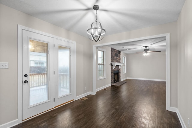 unfurnished living room with a large fireplace, dark hardwood / wood-style flooring, and ceiling fan with notable chandelier