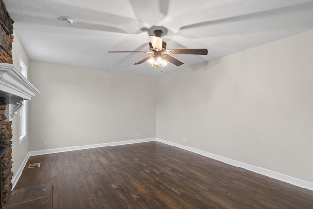 unfurnished living room featuring a fireplace, plenty of natural light, dark hardwood / wood-style floors, and ceiling fan