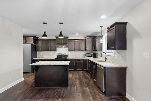 kitchen with sink, backsplash, a center island, decorative light fixtures, and stainless steel appliances