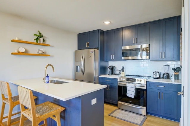 kitchen featuring kitchen peninsula, a breakfast bar, blue cabinets, sink, and appliances with stainless steel finishes