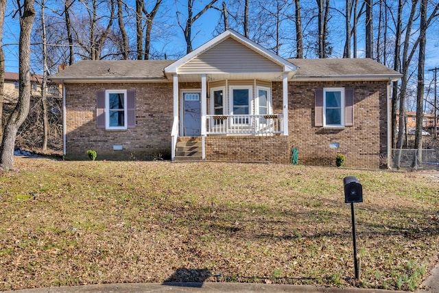 view of front of property with a porch, a front yard, crawl space, and brick siding