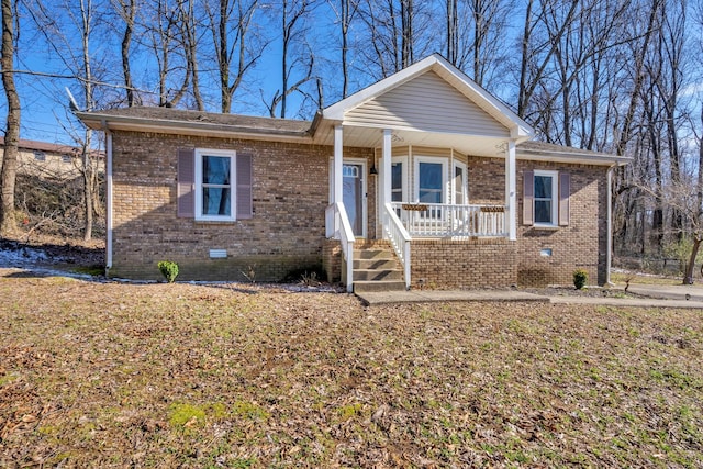 view of front of property with covered porch, brick siding, and crawl space