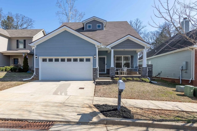 view of front of house with a garage, stone siding, covered porch, and driveway