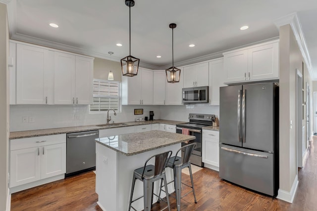 kitchen with sink, appliances with stainless steel finishes, white cabinets, and a center island