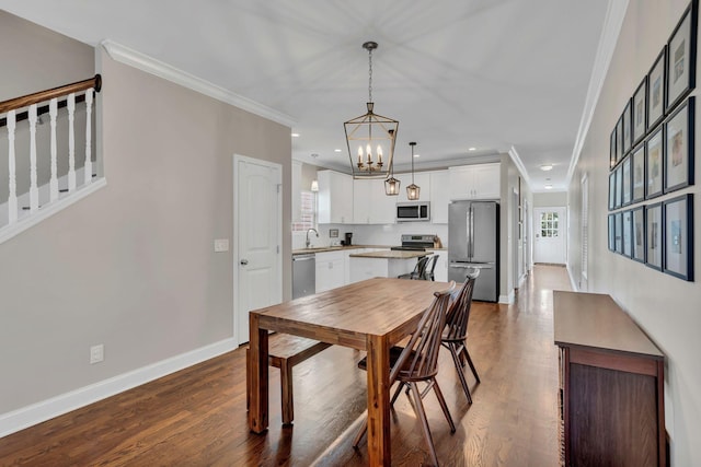 dining space featuring an inviting chandelier, hardwood / wood-style flooring, sink, and ornamental molding