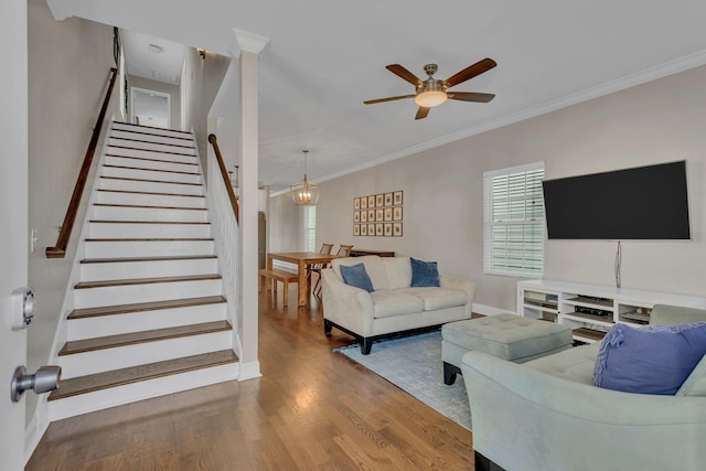 living room featuring ceiling fan with notable chandelier, crown molding, and wood-type flooring