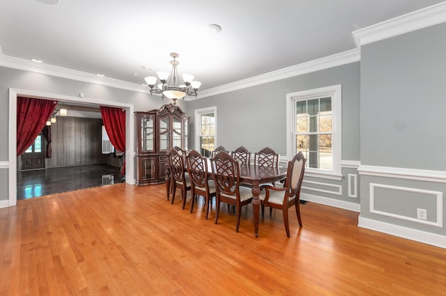 dining space with hardwood / wood-style floors, an inviting chandelier, and crown molding