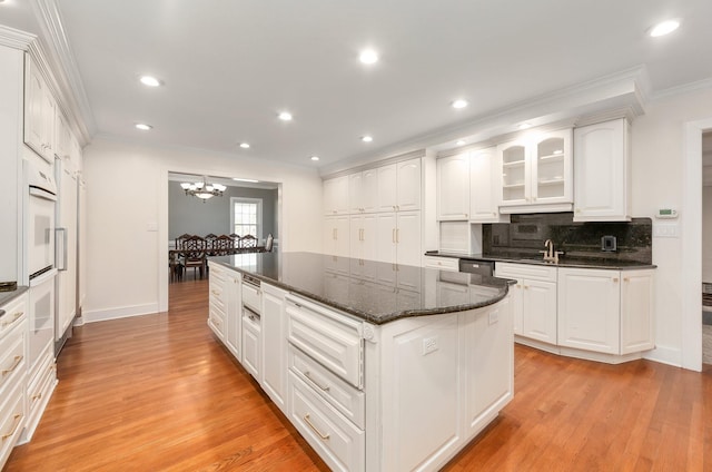 kitchen featuring backsplash, a center island, white cabinetry, light hardwood / wood-style floors, and crown molding