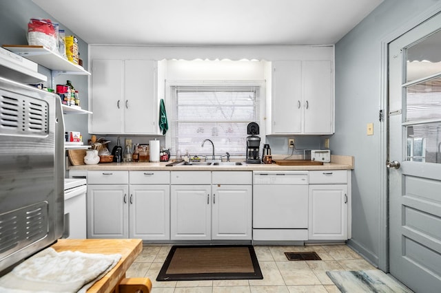 kitchen with white cabinets, light tile patterned floors, dishwasher, and sink